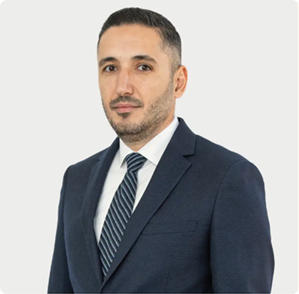 A man in a suit and tie standing up against a white wall.